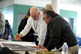 Two men look over a county flood map at an open house