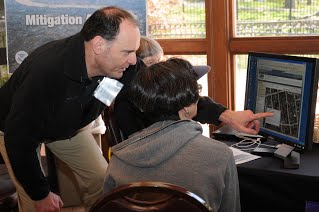 A FEMA representative shows flood hazard data on a computer to one of the people who attended an Open House
