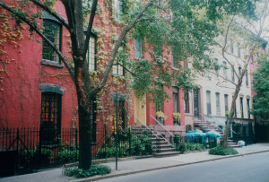 A row of attached residential buildings in a New York City neighborhood.